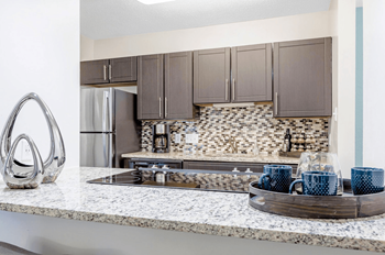 A kitchen with a marble countertop and a tray of blue mugs.