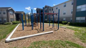 Orlando apartment for rent - Red and blue playground set in a bed of mulch with building exteriors in the background