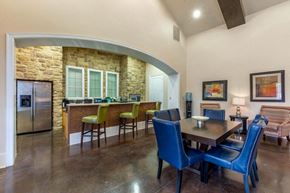 Dallas apartment for rent - Clubhouse kitchen with a large wooden table, blue chair, and a kitchen island