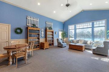 Denton apartment for rent - A living room with a dining table and chairs, a bookcase, and a window with a view of trees.