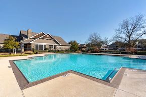 Denton apartment for rent - Swimming pool with tanning deck, clubhouse exterior, green trees, and clubhouse in the background