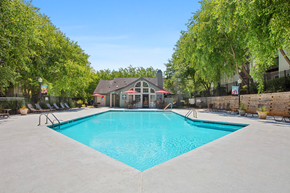 Gastonia apartment for rent - A large swimming pool surrounded by trees and a building in the background.
