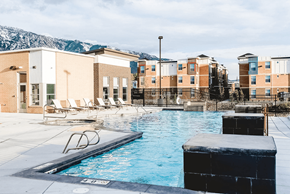 Sandy apartment for rent - A swimming pool in front of a building with a mountain in the background.