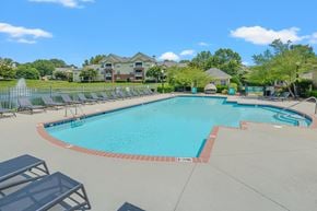 Cary apartment for rent - A large swimming pool surrounded by lounge chairs and trees.
