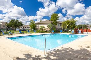 Kissimmee apartment for rent - A large swimming pool surrounded by a fence and trees.