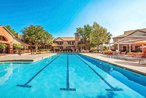 Carrollton apartment for rent - Swimming Pool and Sun Deck with Lounge Chairs with Trees and Building Exteriors in the Background