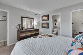 Raleigh apartment for rent - A bedroom with a large bed and a dresser with a mirror above it.