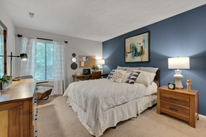 Raleigh apartment for rent - A bedroom with a large bed and a painting on the wall.