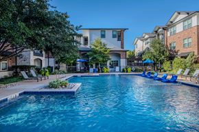 Dallas apartment for rent - A swimming pool surrounded by lounge chairs and trees.