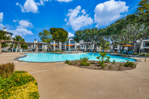 Roanoke apartment for rent - A large swimming pool surrounded by a sandy area and green plants.