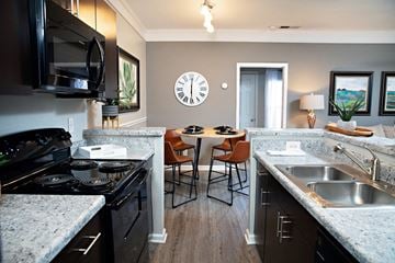 Durham apartment for rent - A kitchen with a black stove top oven and a black microwave above it.