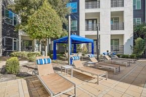 Dallas apartment for rent - A sunny day at the pool with chairs and a canopy.