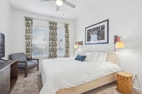 Dallas apartment for rent - A bedroom with a bed, chair, and a ceiling fan.