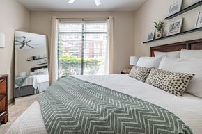 Knoxville apartment for rent - A bedroom with a large bed and a window overlooking a garden.