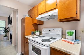Douglasville apartment for rent - A kitchen with a white stove top oven and wooden cabinets.