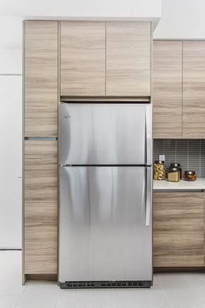 Miami apartment for rent - A stainless steel refrigerator in a modern kitchen with wooden cabinets.