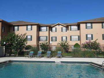 Orlando apartment for rent - A swimming pool in front of a building with a row of chairs.