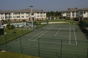 Orlando apartment for rent - A tennis court surrounded by a green fence and apartment buildings in the background.