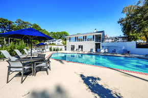 La Grange apartment for rent - A pool with chairs and umbrellas in front of a house.