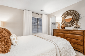 Matthews apartment for rent - A bedroom with a large bed, a wooden dresser, and a mirror on the wall at Paces Pointe Apartment Homes, North Carolina