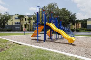 Sanford apartment for rent - Playground jungle gym and playground slides in a bed of mulch with trees, and building exteriors in the background
