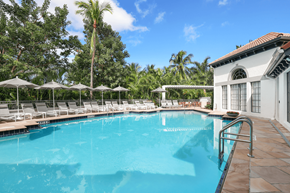 Aventura apartment for rent - A large swimming pool surrounded by trees and lounge chairs.