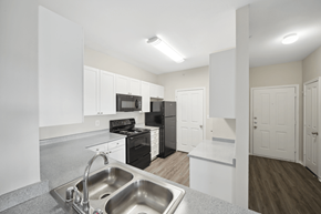 Denton townhouse for rent - a kitchen with white cabinets and a stainless steel sink