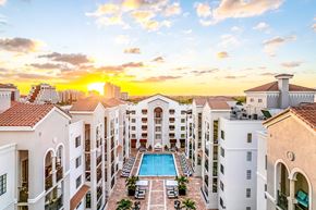 Coral Gables apartment for rent - A sunset view of a pool surrounded by apartment buildings.