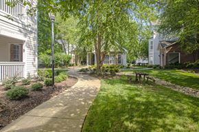 Nashville apartment for rent - a pathway through a grassy area with trees and buildings in the background