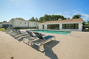 St. Marys apartment for rent - a swimming pool with chaise lounge chairs and clubhouse in the background
