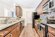 Charlotte apartment for rent - A kitchen with wooden cabinets and a black stove top oven. at Southpark Commons Apartment Homes, Charlotte