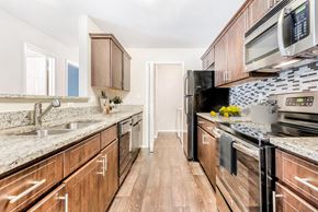 Charlotte apartment for rent - A kitchen with wooden cabinets and a black stove top oven. at Southpark Commons Apartment Homes, Charlotte