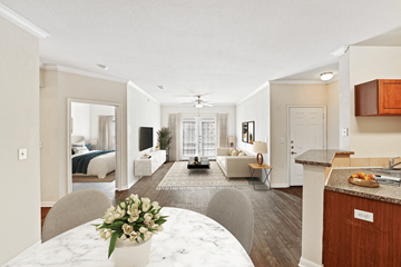 Tyler apartment for rent - A well-lit, spacious living room with a kitchen area and a dining table set with a vase of flowers.