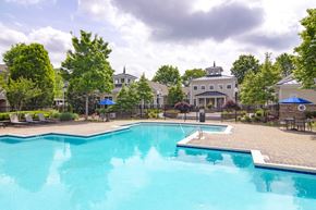 Austell apartment for rent - A large swimming pool surrounded by trees and a building in the background.