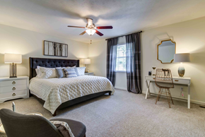 Knoxville apartment for rent - staged bedroom with carpeted flooring, lighted ceiling fan, and window