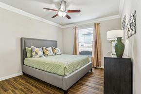 Pflugerville apartment for rent - A bedroom with a bed, a ceiling fan, and a wooden floor.