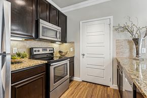 Pflugerville apartment for rent - A kitchen with a white door and a black microwave above the stove.