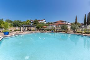 Tallahassee apartment for rent - A large swimming pool in a backyard with a fence and a house in the background.