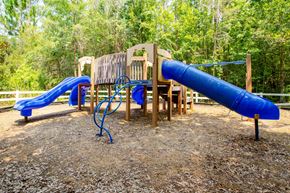 Jacksonville apartment for rent - A playground with a blue slide and a wooden structure.