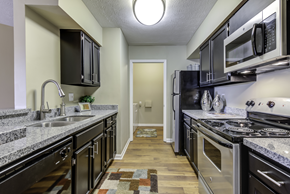 Lexington apartment for rent - Gally style kitchen with stainless steel appliances, undermount sink, granite counters, and wood style flooring leading to the laundry room.