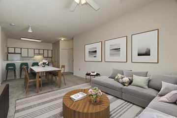 Waldorf apartment for rent - A living room with a grey couch, a wooden coffee table, and a dining table with chairs.