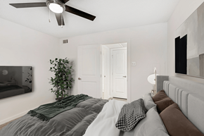 Plano apartment for rent - Virtually staged bedroom with wall mounted television, artificial tree, ceiling fan with light and wall art