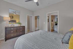 Morrisville apartment for rent - A bedroom with a patterned bedspread and a dresser with a mirror above it.