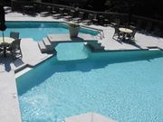 Greensboro apartment for rent - A pool with a concrete edge and a concrete patio with chairs and a table.