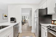 Cary apartment for rent - A modern kitchen with a black refrigerator and white cabinets. at Woodlyn on the Green Apartment Homes, Cary, North Carolina