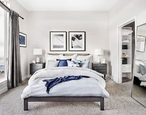 Denver apartment for rent - A bedroom with a large bed and a mirror on the wall.