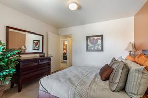 Mesa apartment for rent - Model Bedroom with Bed and Dresser with Mirror Mounted Above it Next to Plant