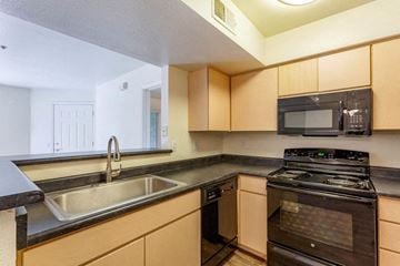 Mesa apartment for rent - A kitchen with a black stove top oven and a black microwave above it.