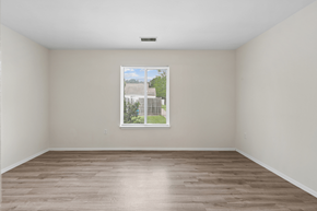 Waldorf apartment for rent - Empty room with a window showing a view of a building and trees.
