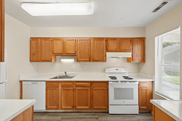 Waldorf apartment for rent - A kitchen with wooden cabinets and white appliances.